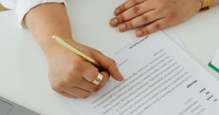 A person signing a contract at a table.