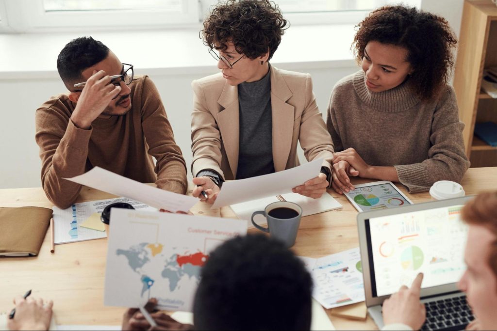 Several office workers are in discussion at a table.